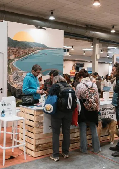 Desk espositivo con grafica costiera e visitatori in fiera