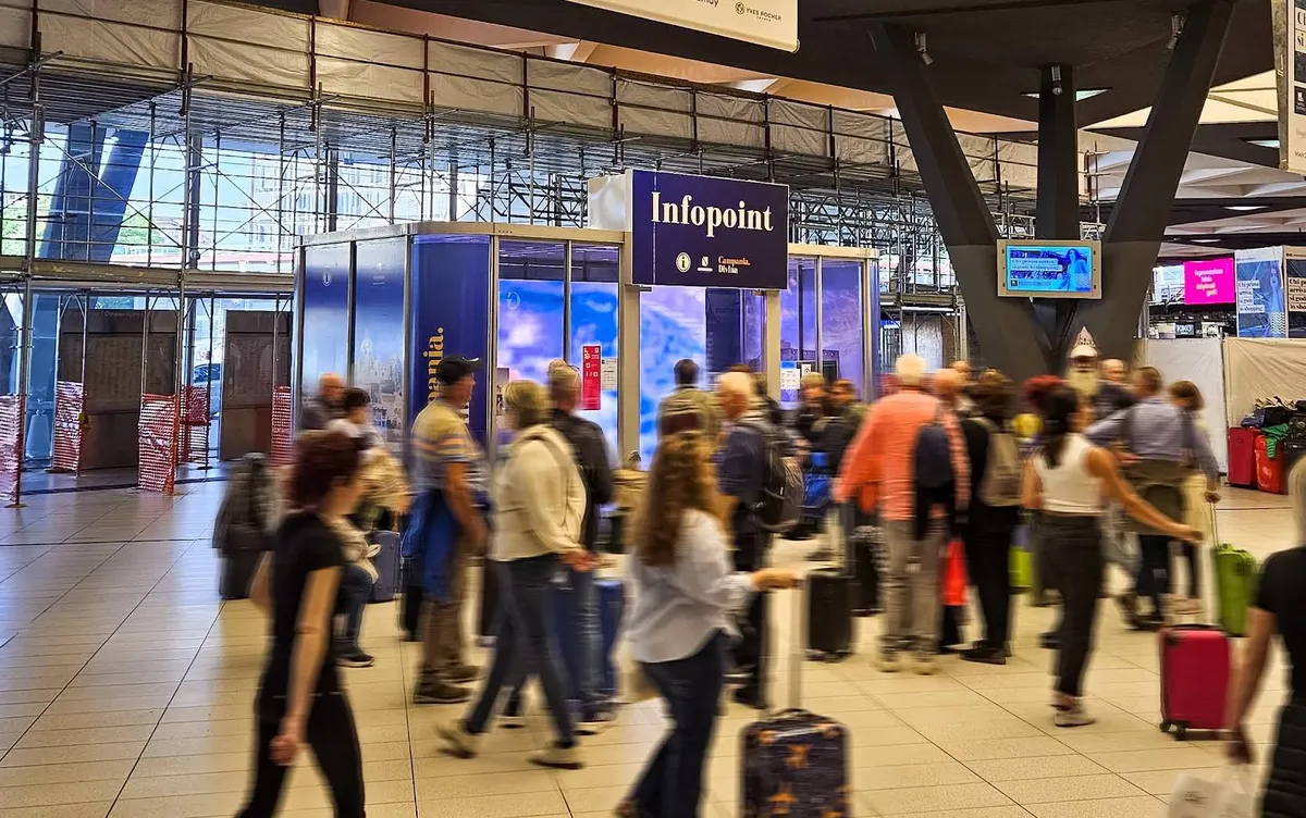 Infopoint turistico Campania.Divina in una stazione, con viaggiatori in movimento