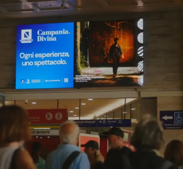 Schermo digitale «Ogni esperienza, uno spettacolo» sopra i passeggeri in stazione